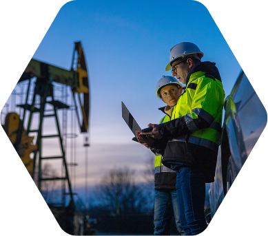 Man and woman in hard hats with laptop in oil fields