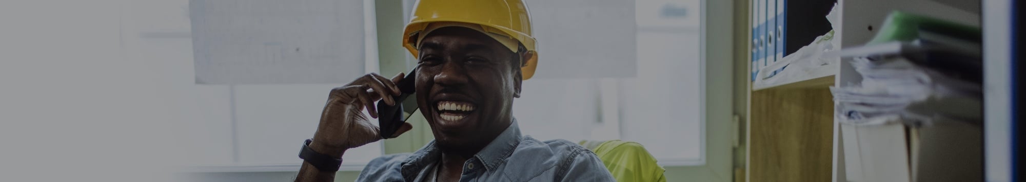 Smiling man in yellow hard hat talking on the phone