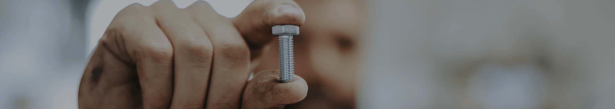 Close-up of a man holding a bolt between two fingers